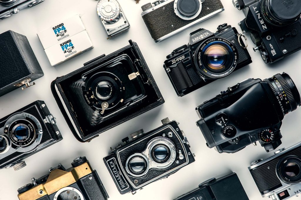 An image of several cameras with a white background, showcasing a collection of different camera types.